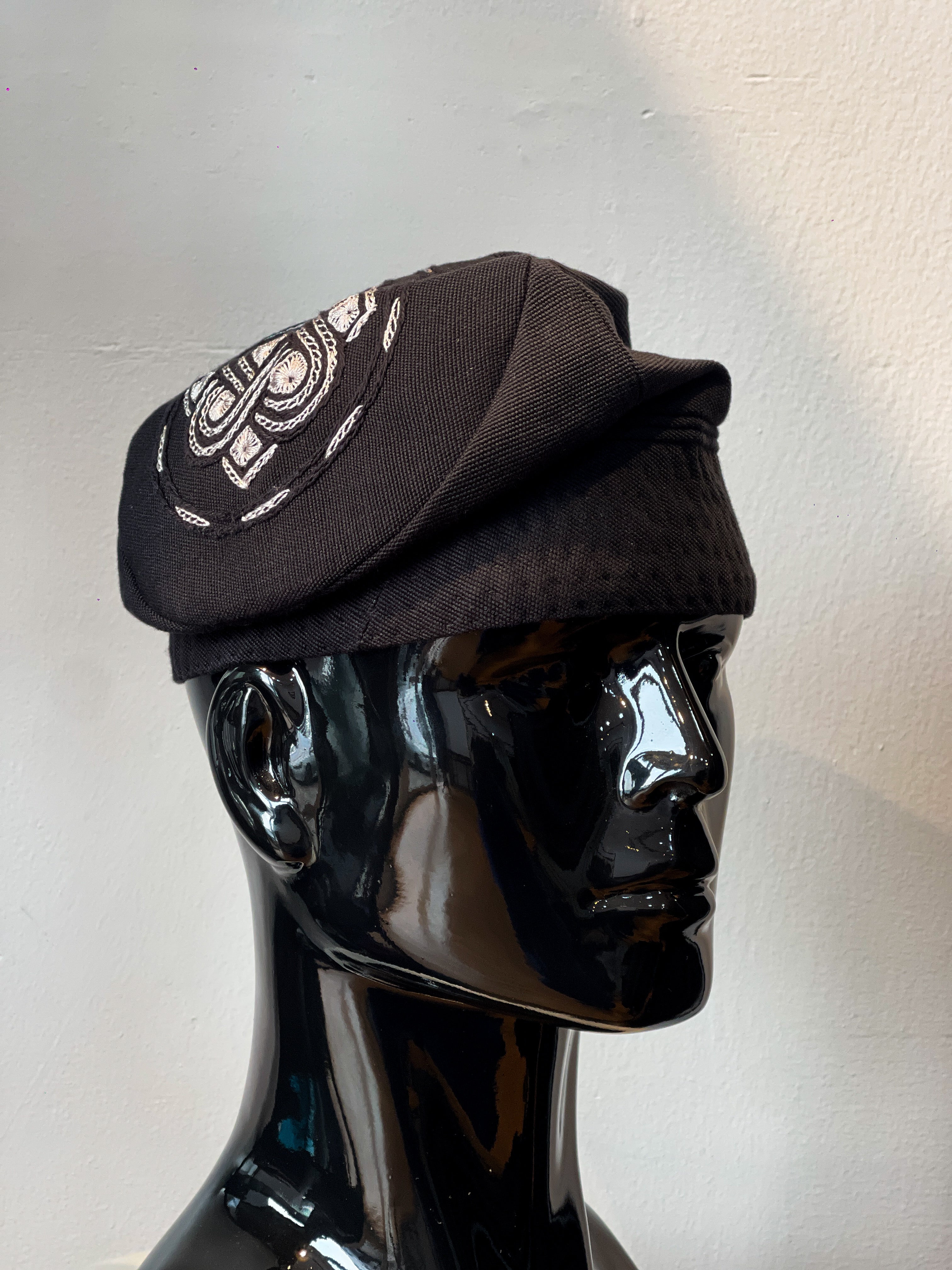 A black Nigerian aso oke cap with grey embroidery on top
