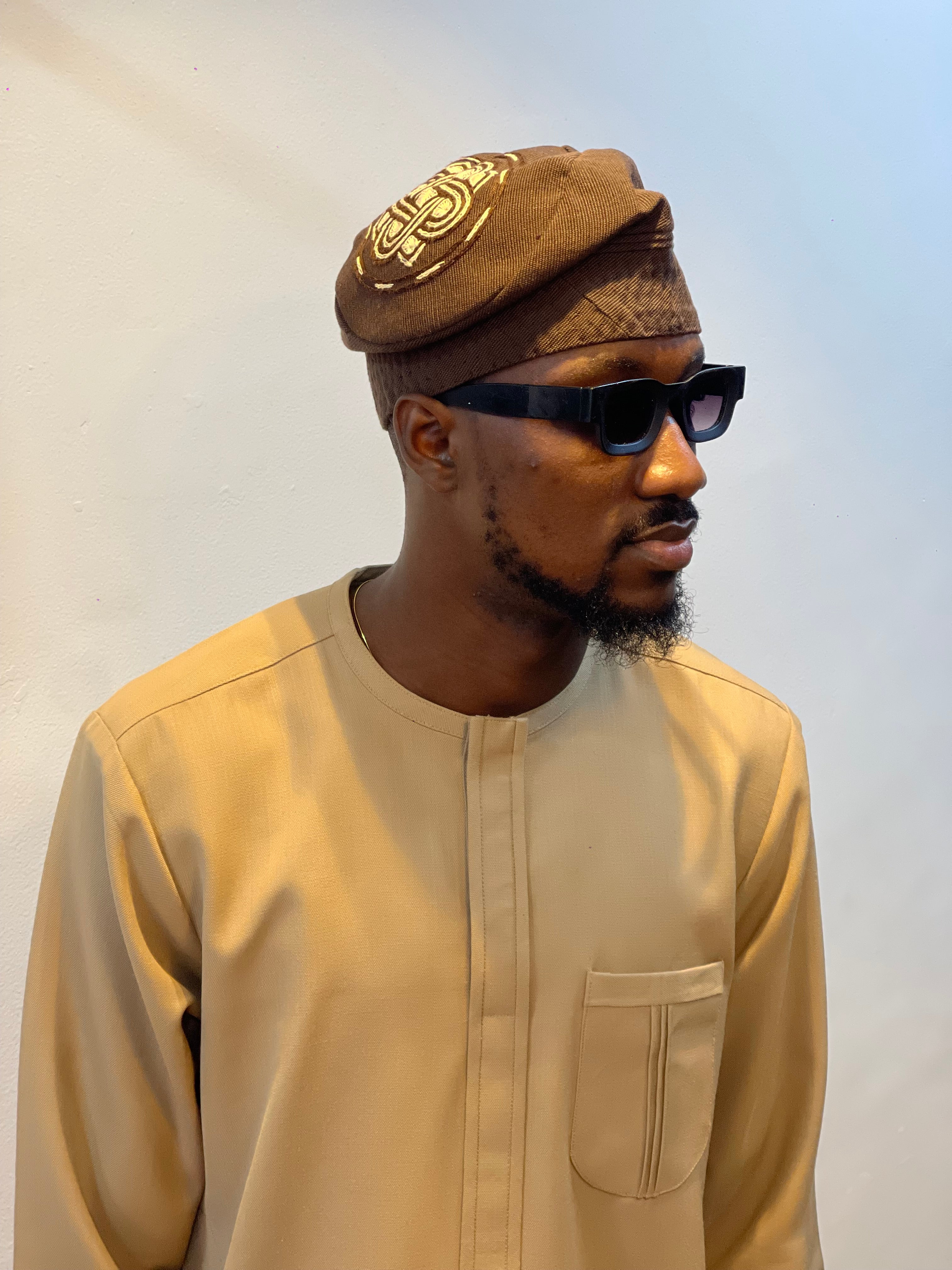 Nigerian man wearing a carton brown kaftan with brown cap and embroidery 